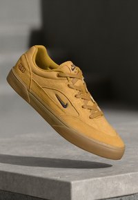 Żółte zamszowe buty do skateboardu mają niską cholewkę, sznurowania, czarne logo oraz beżową gumową podeszwę. Zauważalny detal "58".