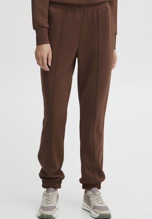 Brune joggebukser laget av mykt stoff, med en avslappet passform, elastisk midjebånd og smale mansjetter, samt subtile sømdetaljer langs sømmene.