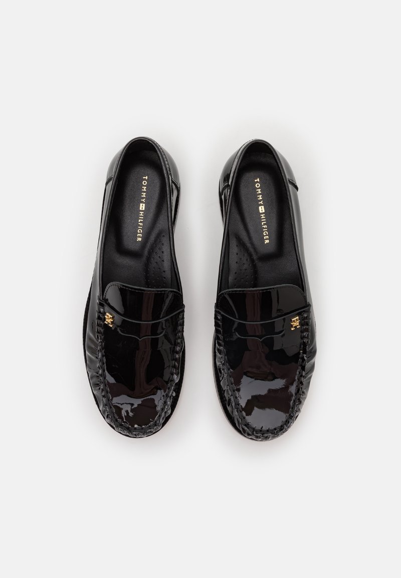 Schwarze Lacklederslipper mit abgerundetem Zeh, ausgestattet mit einer geflochtenen Akzentuierung und goldfarbener Logo-Applikation auf der Vorderseite, auf einer beigen Innensohle.