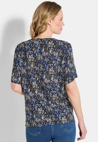 Kurze Ärmel Bluse mit einem abstrakten Muster in Blau, Grau und Grün. Hergestellt aus leichtem Stoff mit einer lockeren Passform und abgerundetem Saum.