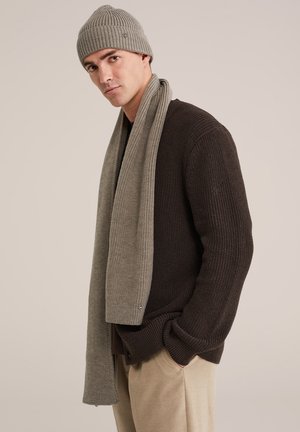 Tumši brūns adīts džemperis, gaiši pelēka adīta šalle un saskanīga cepure; visiem ir ribota tekstūra un vienkāršs dizains.