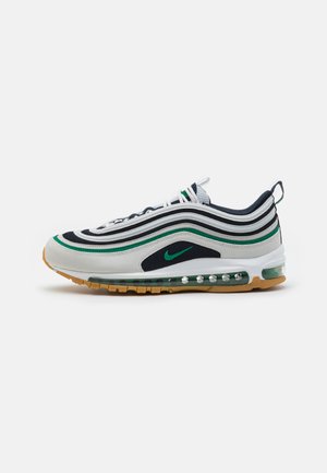 Nike Air Max 97 sneakers met een witte, zwarte en groene kleurenschema, een golfpatroon in de bovenkant, en gemaakt van mesh en leer, met een zichtbare luchtunit.