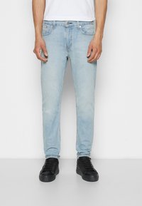 Jasnoniebieskie dżinsy o slim fit, pięć kieszeni, delikatne przetarcia i zapięcie na metalowy guzik. W zestawie z czarnymi, sznurowanymi trampkami.