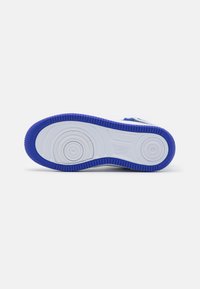 Sola de sapatilha atlética azul e branca com um grip de borracha texturizada, padrões circulares e uma borda elevada para tração.