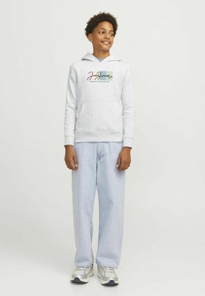 Sweat à capuche gris avec un logo graphique sur la poitrine, associé à un jean baggy bleu clair et des baskets argentées, arborant un design de pull classique.