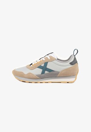 Zapatillas deportivas en gris claro, beige y verde azulado. Cuentan con materiales de ante y malla, cordones blancos, suela texturizada y una lengüeta de talón con lazo.