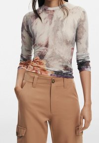 Top attillato a maniche lunghe con un motivo floreale nei toni di viola, beige e arancione; presenta un collo rotondo e dettagli a coste.