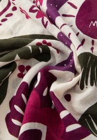 Tissu à motif floral, mettant en avant des couleurs magenta, vert et blanc. Matériau en coton doux et texturé avec des motifs en spirale complexes.