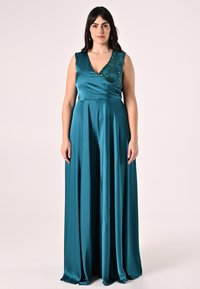 Tuta in raso turchese con scollo a V e design floreale in paillettes su una spalla. Stile ampio e fluente con gamba larga e tessuto liscio.