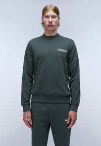 Dunkelgrüner Sweatshirt aus weichem Material, mit Rundhalsausschnitt, gerippten Bündchen und kleinem Logo auf der Brust. Kombiniert mit passenden Jogginghosen.