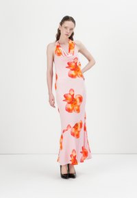 Halter-neck rosa kjole med stort oransje floralmønster, tettsittende silhuett og flagrende kant. Modellen har på seg svarte høye hæler.