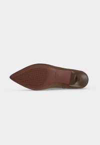 Semelle de chaussure marron à bout pointu avec zone de grip texturée et talon lisse, présentée devant un fond gris clair uni.