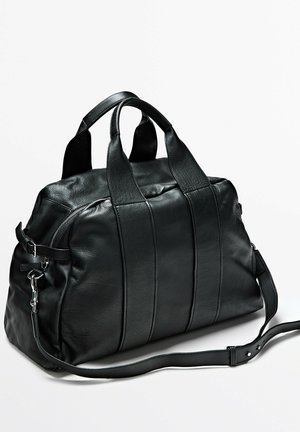 Schwarze Leder-Reisetasche mit zwei Griffen und verstellbarem Schulterriemen, ausgestattet mit einer seitlichen Schnalle und Reißverschluss.