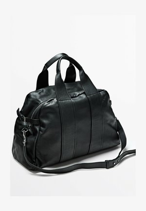 Schwarze Leder-Reisetasche mit zwei Griffen und verstellbarem Schulterriemen, ausgestattet mit einer seitlichen Schnalle und Reißverschluss.