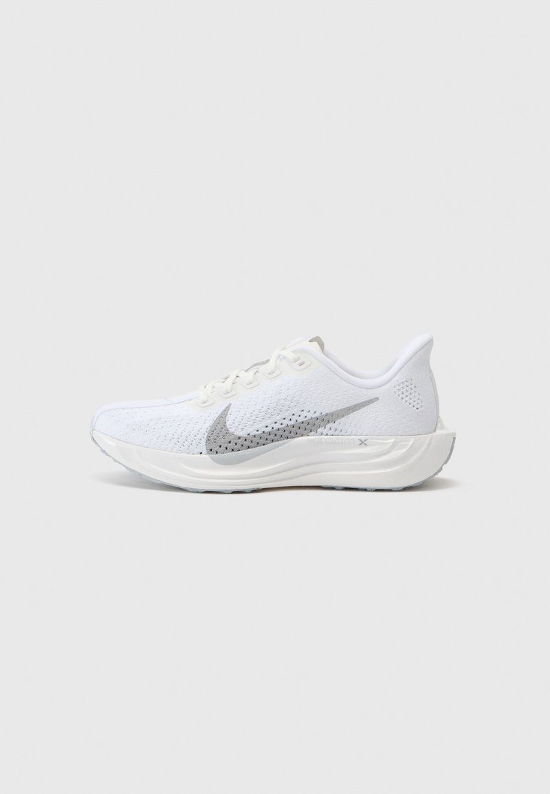 Bela atletska čevlja z mrežno zgornjo ploščo, srebrnim Nikeovima logotipom, podplatom z oblazinjenjem in teksturiranimi poudarki. Lahka zasnova za udobje in fleksibilnost.
