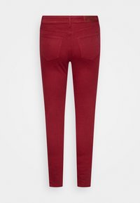 Jeans rojos ajustados con seis bolsillos, con una textura suave y un parche de cuero en la espalda de la cintura.