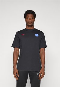 Sort kortærmet Nike skjorte med rød logo og blå Paris Saint-Germain emblem på brystet. Glat stof, rund halsudskæring, afslappet pasform.