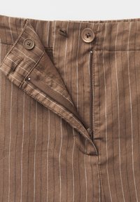 Brown pinstriped pants with zipper partially open and two brown buttons, one sewn on waistband and one on the inner flap.