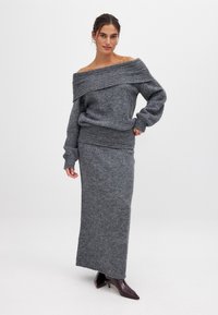 Grauer gestrickter Pullover mit schulterfreier Gestaltung und langen Ärmeln, kombiniert mit einem passenden langen Rock. Glatte Textur und figurbetonte Silhouette.