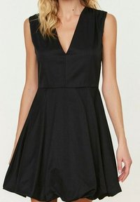 Robe noire sans manches avec un décolleté en V profond, un corsage structuré et une jupe évasée qui se resserre à l'ourlet pour créer une forme de bulle. Tissu lisse.