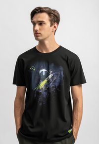 Zwarte katoenen t-shirt met een kleurrijke, ruimte geïnspireerde grafiek, inclusief planeten, sterren en een komeetontwerp. Korte mouwen en een ronde halslijn.