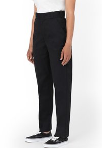 Svart, högmidjade byxor med rak passform. Slät textur, i kombination med en vit skjorta och svarta sneakers. Har bältesöglor.