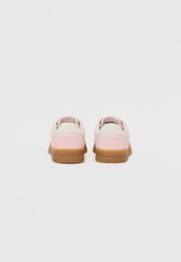 Rosa lädersneakers med vita detaljer och en gummisula. Rundad design med vadderad krage och synlig logotyp på hälen.