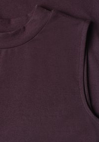 Gros plan d’un haut sans manches violet foncé à col roulé montrant la texture du tissu et des coutures nettes autour de l’encolure et de l’emmanchure.