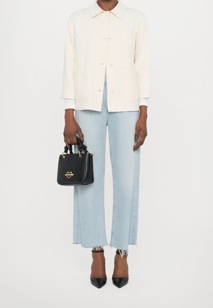 Slonovinově bílá bavlněná bunda, světle modré široké džíny a černá kabelka s kroucenými úchyty a zlatým logem ve tvaru srdce, doplněné černými špičatými podpatky.