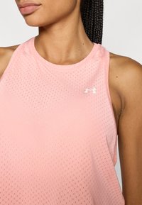 Top desportivo cor de rosa claro com textura perfurada e respirável e decote redondo. Apresenta um pequeno logótipo branco da Under Armour.