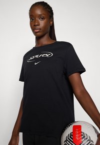 Svart bomull t-skjorte med "SPURS" logo i sølv, rund hals, korte ermer, sammen med en hvit og svart mønstret fotball.