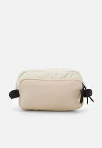 Borsa a tracolla rettangolare realizzata in morbido tessuto color crema e beige. Presenta una zip superiore, dettagli in metallo nero e una tracolla laterale regolabile.