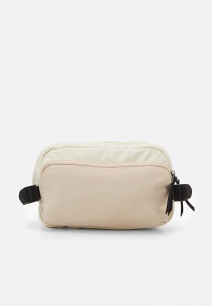 Borsa a tracolla rettangolare realizzata in morbido tessuto color crema e beige. Presenta una zip superiore, dettagli in metallo nero e una tracolla laterale regolabile.
