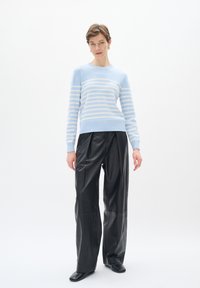 Maglione a righe blu chiaro con righe orizzontali avorio, collo rotondo, polsini a coste, abbinato a pantaloni in pelle nera a vita alta e scarpe nere.
