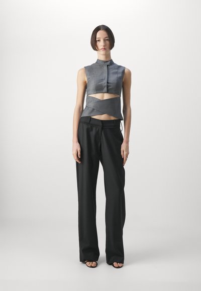 Gray cropped top with a high neck and cut-out detail, paired with black wide-leg trousers and minimalist black sandals. Smooth fabric texture.