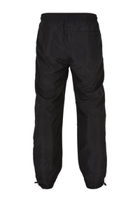 Pantalones negros, ligeros, impermeables, con un corte relajado, cinturilla elástica y puños ajustables. Cuenta con un bolsillo trasero.