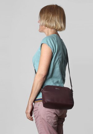 Borsa a tracolla in pelle bordeaux con una texture liscia e un marchio discreto. Presenta una lunga tracolla e una forma rettangolare.
