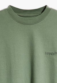 Zelené bavlněné tričko s kulatým výstřihem, s jemně vyšitým logem Levi's v barvě trička na přední straně. Měkká textura, jednoduchý design.