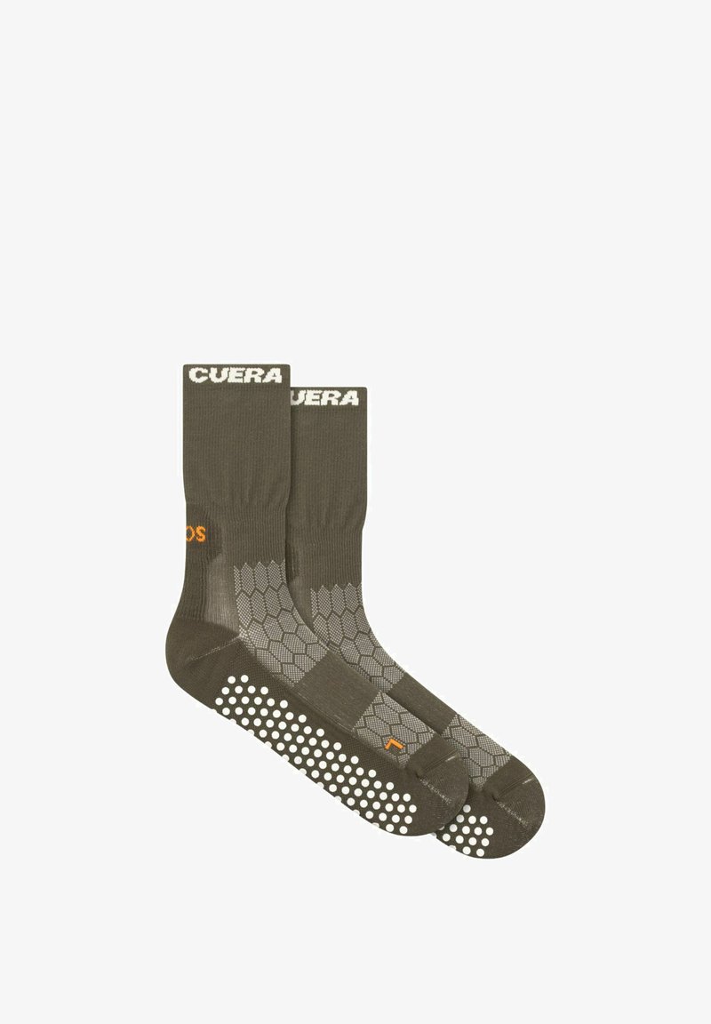 Paire de chaussettes antidérapantes vert foncé avec motifs hexagonaux et points blancs antidérapants sous les semelles, avec des détails de texte blancs et orange.