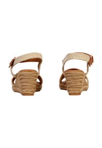 Vinkelsandaler med en vævet overdel i beige, tan rebdetaljer på hælen og en spænde rem bagpå for en sikker pasform.