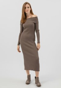 Schulterfreies, geripptes Midikleid in Taupe, mit langen Ärmeln und figurbetonter Silhouette, kombiniert mit grauen Stiefeletten.