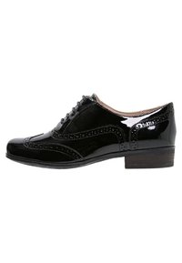 Chaussure Oxford en cuir noir brillant avec détails brogue, lacets sur le devant et petit talon en bois, vue de côté sur fond blanc.