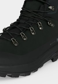 Μαύρο ορειβατικό μποτάκι με μεταλλικά γάντζους για κορδόνια, παχιά προφιλωμένη σόλα και υλικό Gore-Tex σχεδιασμένο για αδιάβροχη ανθεκτικότητα και υπαίθρια χρήση.