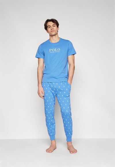 T-shirt azul em algodão com o logotipo "POLO", combinado com calças de pijama azuis com um padrão repetido de logotipo branco, punhos elásticos e bolsos laterais.