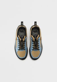 Blå og tan tekstil joggesko med svarte snører, gummisåle og merkeheklopper, med en blanding av glatte og teksturerte overflater.