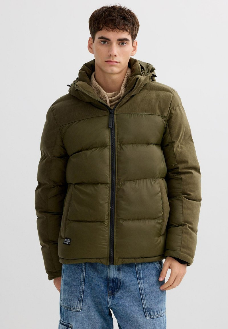 Chaqueta acolchada en verde oliva, con capucha, cierre de cremallera y diseño acolchado horizontal. Confeccionada con un tejido texturizado y bolsillos.