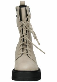 Beige leren enkellaarsjes met een ronde neus, voorzien van een vetersluiting aan de voorkant, een zijrits en een chunky zwarte rubberen zool.