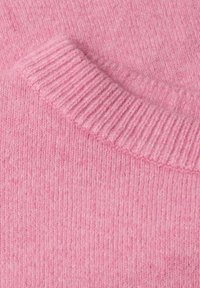 Gros plan d'un pull tricoté rose doux montrant l'encolure côtelée et le tissu texturé.