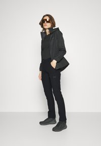 Musthave musta kerge jope kapuutsiga, mille all on must särk, ja see on ühendatud mustade pükstega ning hallide matkajalatsitega. Kuldsed läätsed omavad prille.