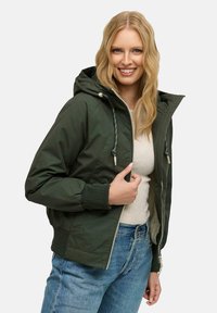Giacca con cappuccio verde scuro, chiusura a zip, polsini a costine e tasche frontali. La fodera interna strutturata aggiunge calore e comfort.